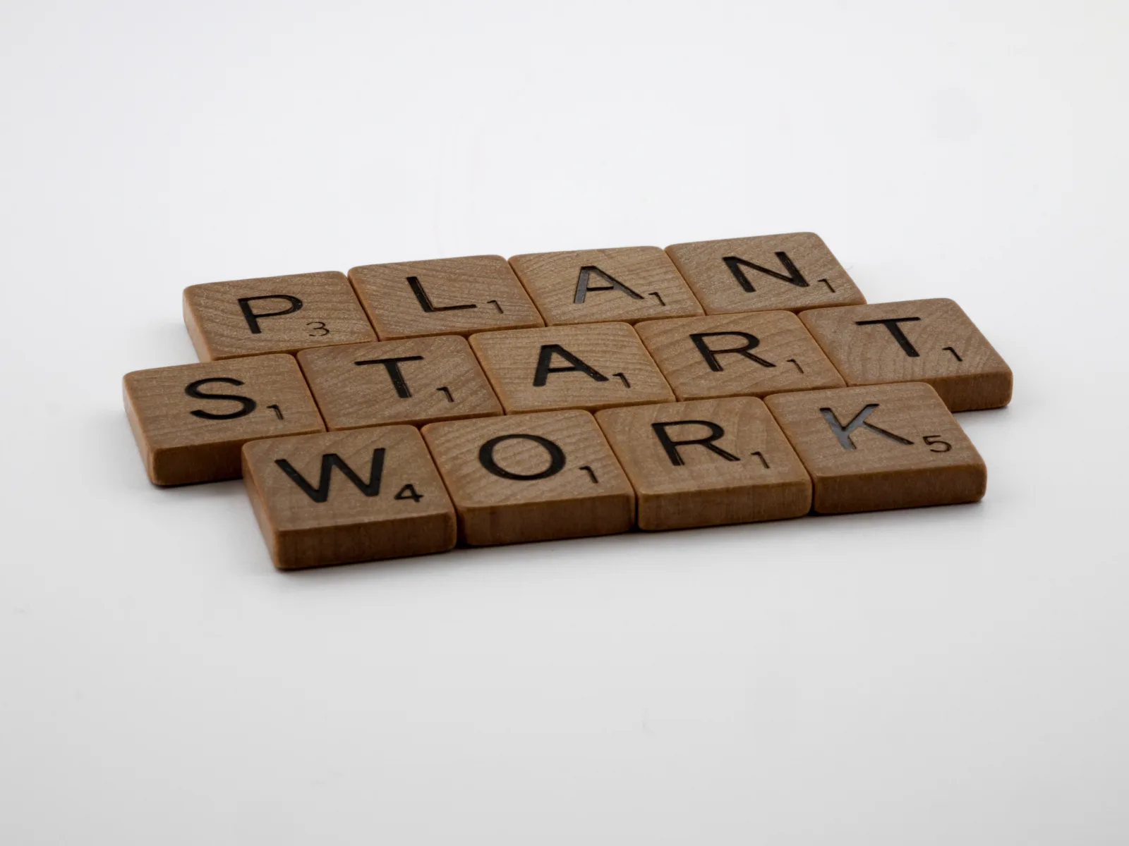 Wooden letter tiles spelling plan, start, and work